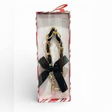 New Day brand Hello Lux Phone Wristlet featuring a gold-toned chain intertwined with black faux leather bows